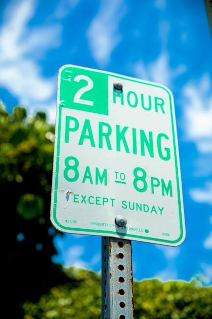 Close-up image of a public parking meter situated on the pavement outside a residential building. The parking meter is grey with a blue section displaying a large white 'P' symbol. The screen shows pa